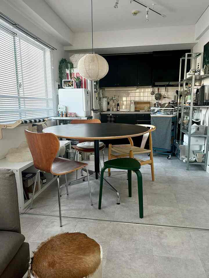 白と黒のトーンのダイニングキッチン、丸いダイニングテーブルと様々な椅子が配置された落ち着いた空間