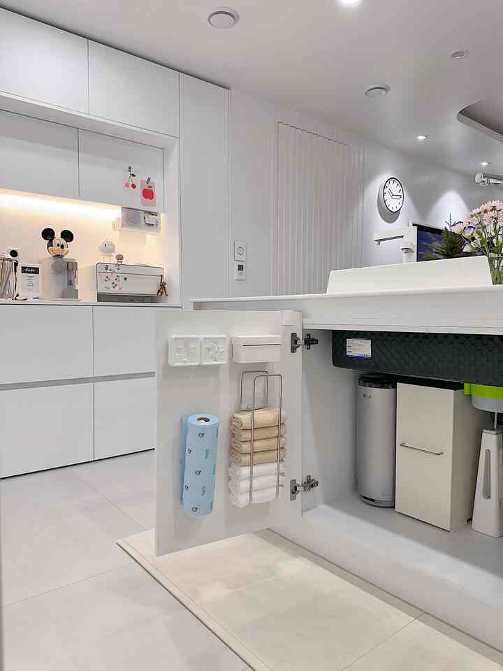 白を基調としたキッチン空間、ミッキーマウスの貯金箱と整った収納が印象的なシンプルモダンなインテリア