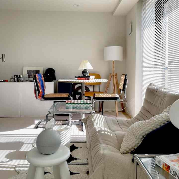 白とナチュラルカラーの2人暮らし向けリビング、モダンなダイニングチェアと照明、居心地の良いソファがある印象的な空間