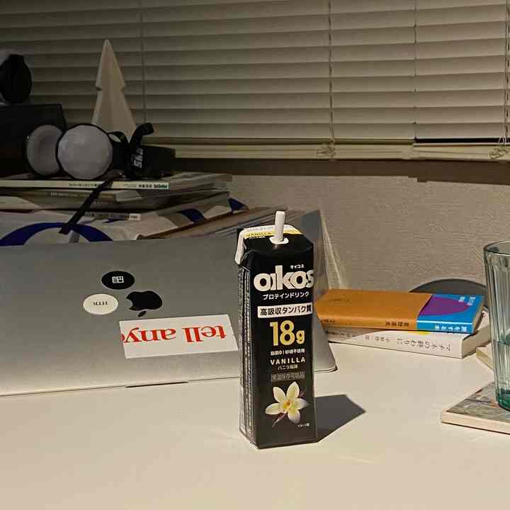 White-toned home office featuring a desk with laptop, beverage carton, and books in a tidy workspace