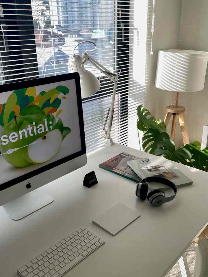 Bright white-toned home office space featuring a desk by the window and greenery, creating a clean and harmonious interior