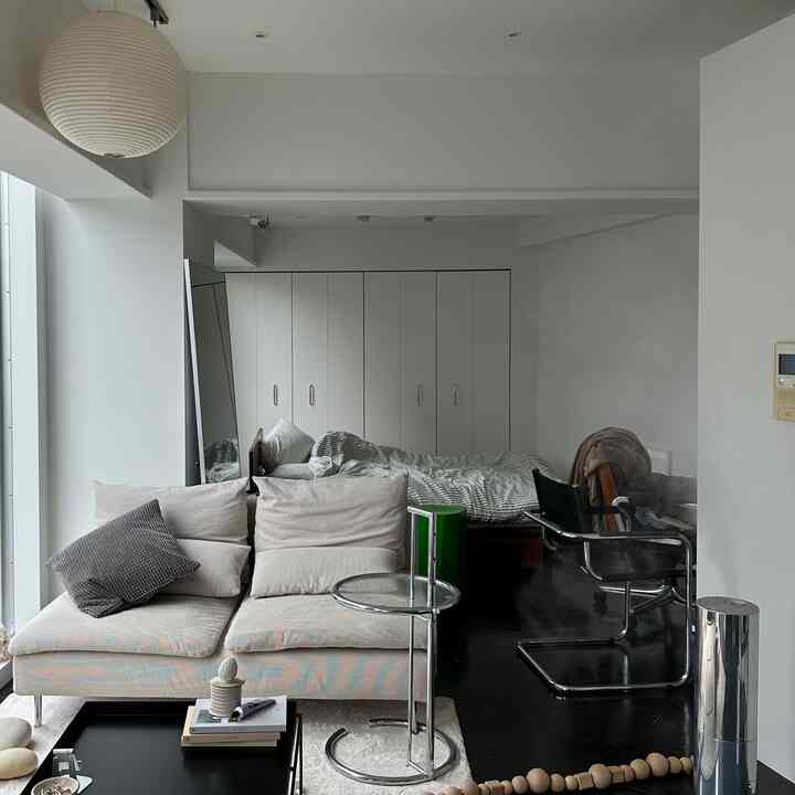 Bright white and beige-toned studio apartment with connected living room and bedroom in a simple style