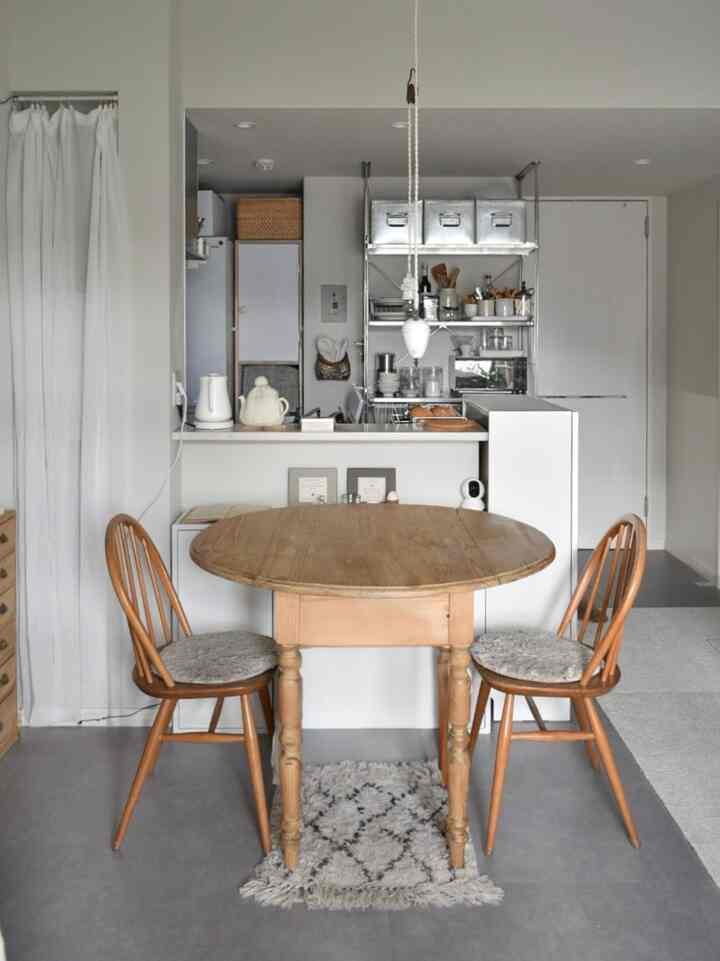 Natural wood tones and white walls create a cozy small kitchen dining area featuring a round wooden dining table and chairs.