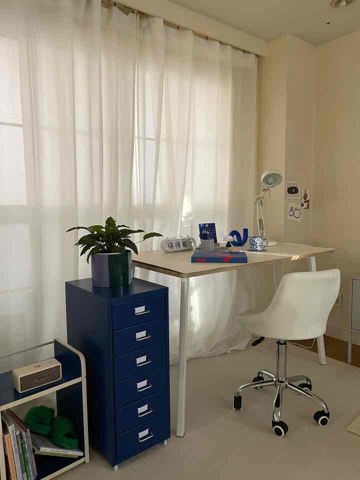 白と青のトーンの1DKワークスペース、シンプルな机と椅子、青い引き出しと植物が配置された雰囲気のあるインテリア