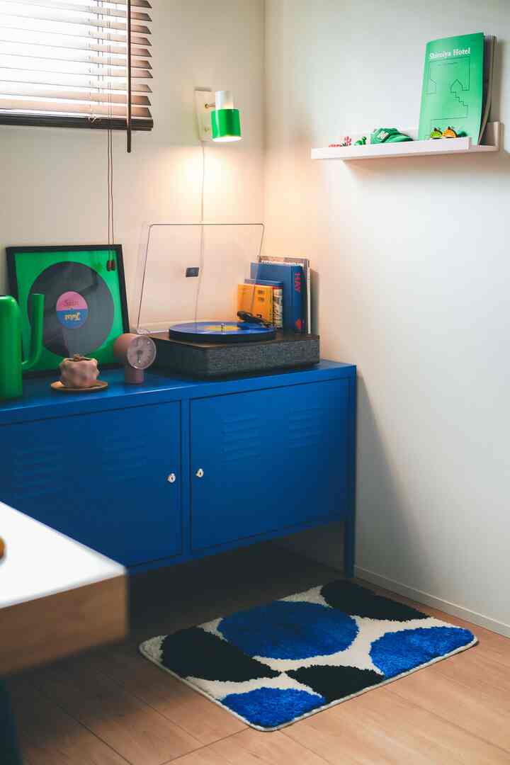Blue and green toned workspace featuring a blue cabinet and dotted pattern rug with a clean, simple atmosphere