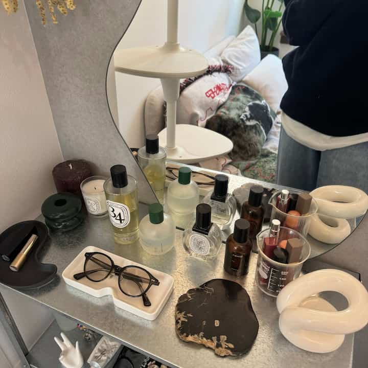 White and gray tone powder room featuring a mirror with shelf holding perfumes and eyeglasses, creating a cozy atmosphere