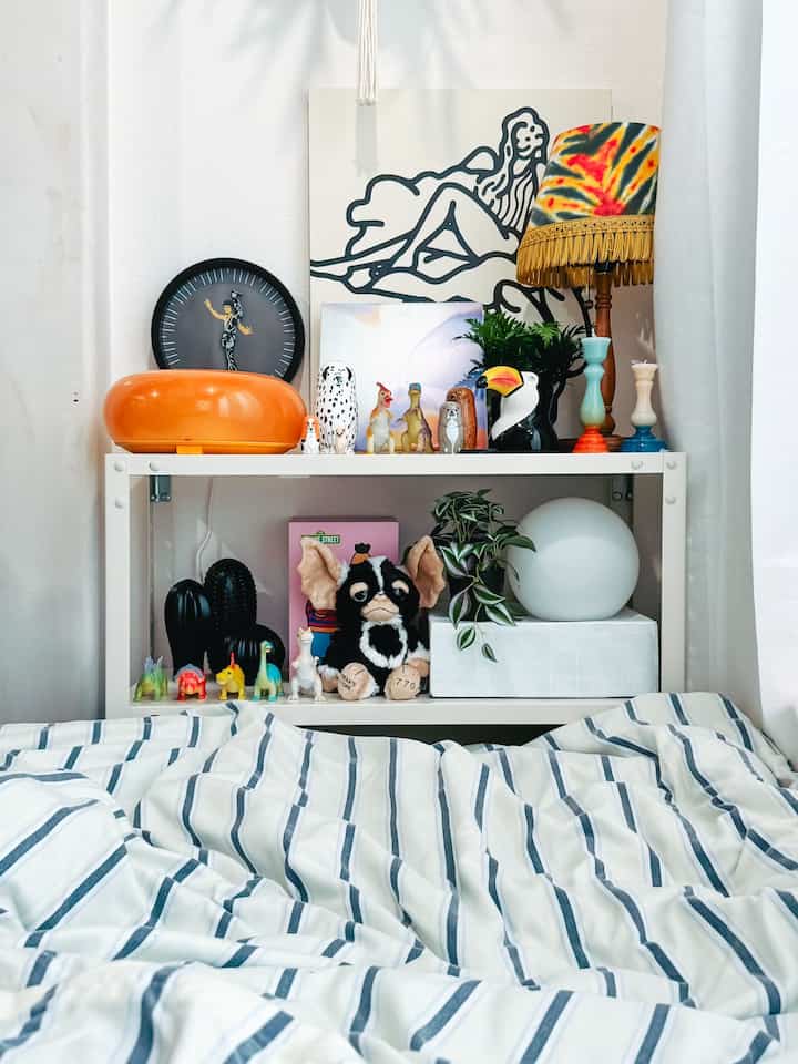 Natural white-toned studio apartment with a display rack featuring various objets and toys, cozy atmosphere