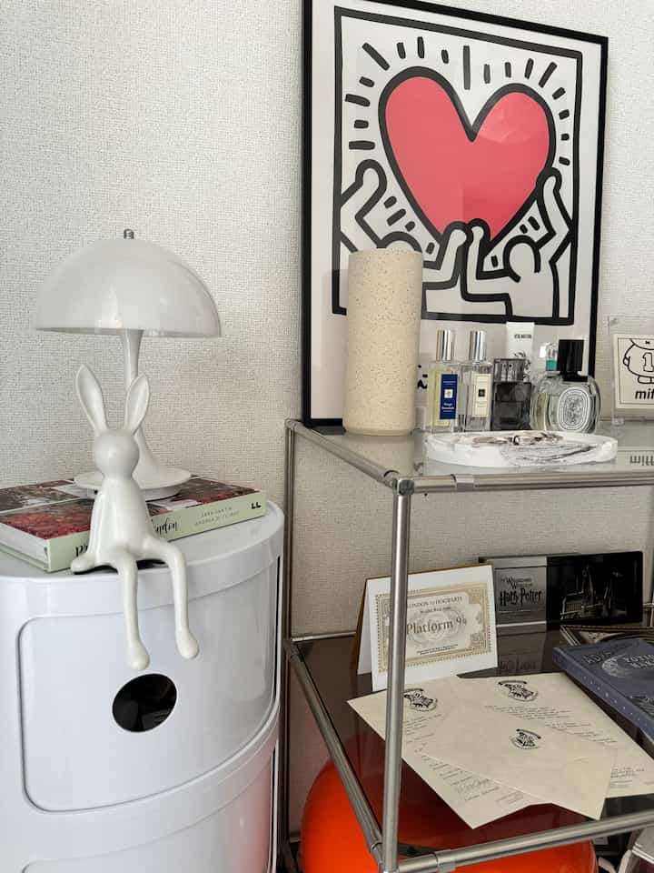 Small space featuring white and transparent materials, white chest of drawers with table lamp, and art poster creating a simple interior