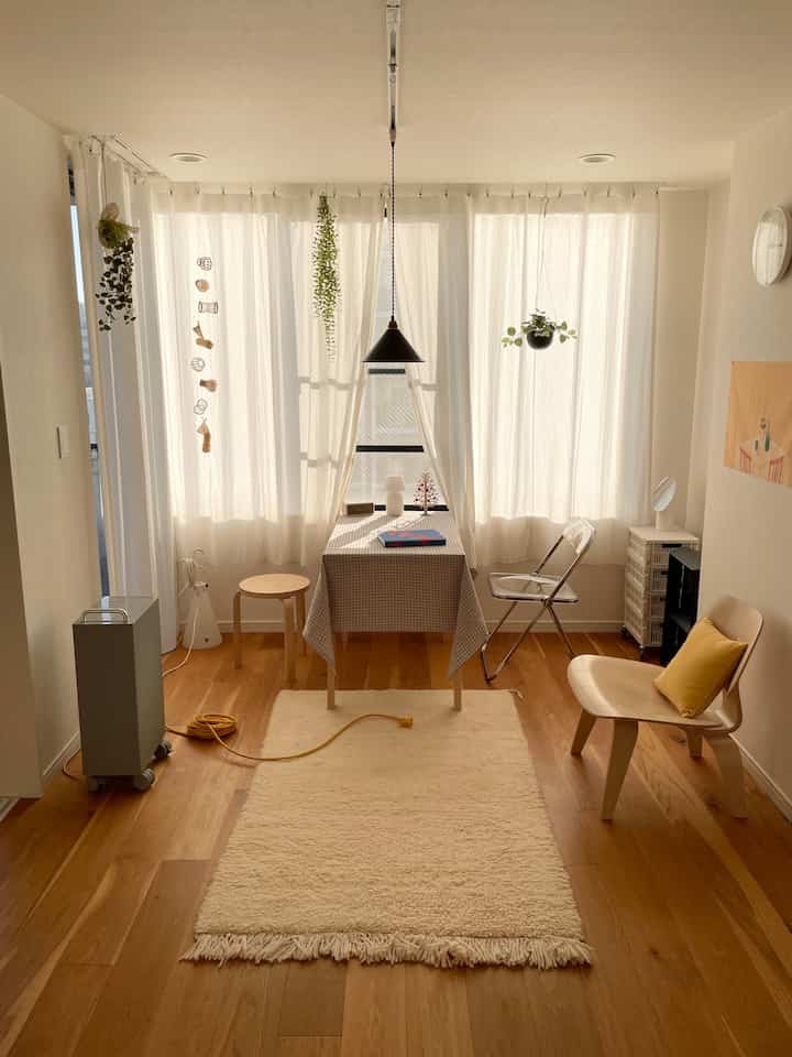 白とナチュラル色調のワンルームリビング、北欧スタイルのシンプルな家具とカーテンが調和する落ち着いた空間