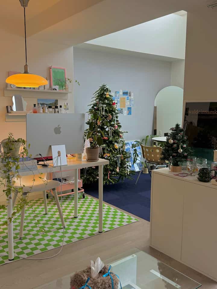 Bright wood tones and white furniture in a cozy studio living room featuring a decorated Christmas tree