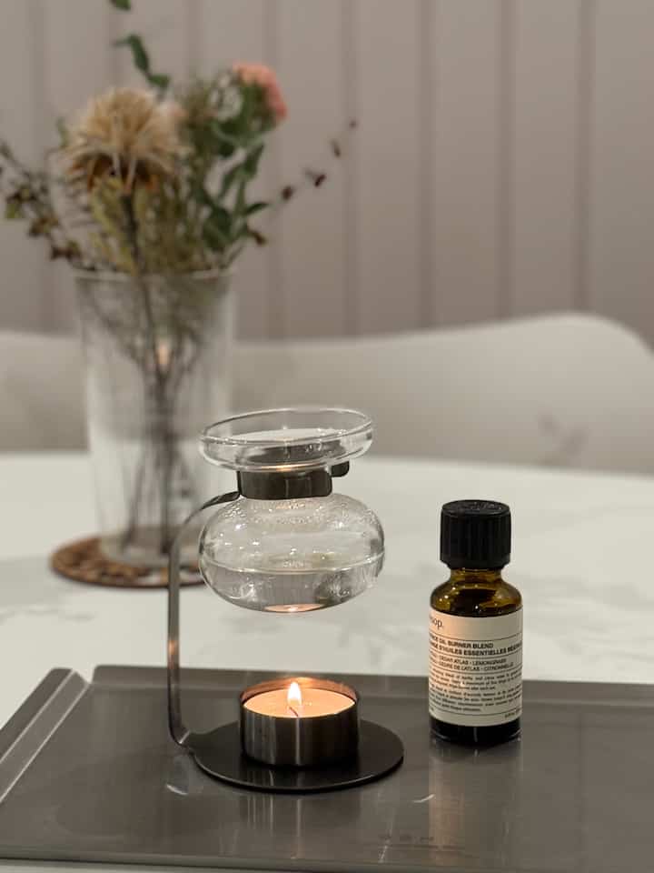 White and black toned dining room featuring an aroma oil burner, candle on a tray, and dried flowers creating a cozy atmosphere