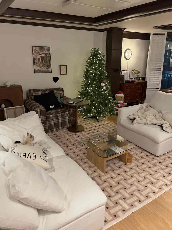 温かみのある木目調と白いソファが調和したリビング、クリスマスツリーとヴィンテージのアームチェアが印象的な空間