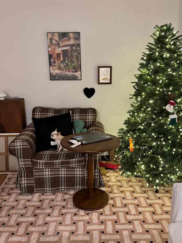 ブラウン系のリビング、チェック柄のアームチェアと円形のサイドテーブル、クリスマスツリーが調和した雰囲気のあるインテリア