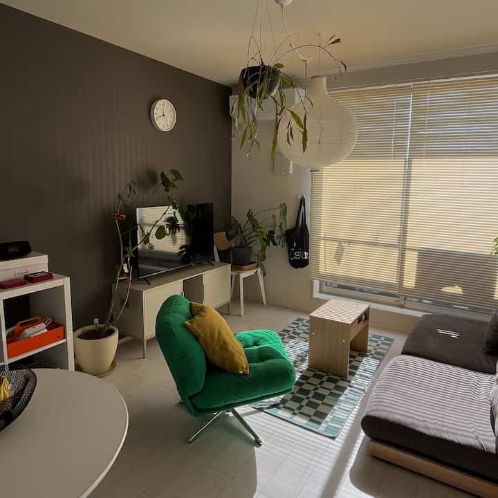 グリーンのアームチェアとブラウンのソファが配置された、自然素材を取り入れたミニマルで北欧風の雰囲気あるリビング