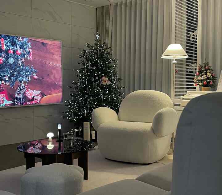 白とナチュラルカラーのリビング、ふかふかのアームチェアとソファ、クリスマスツリーが配置された雰囲気のあるインテリア