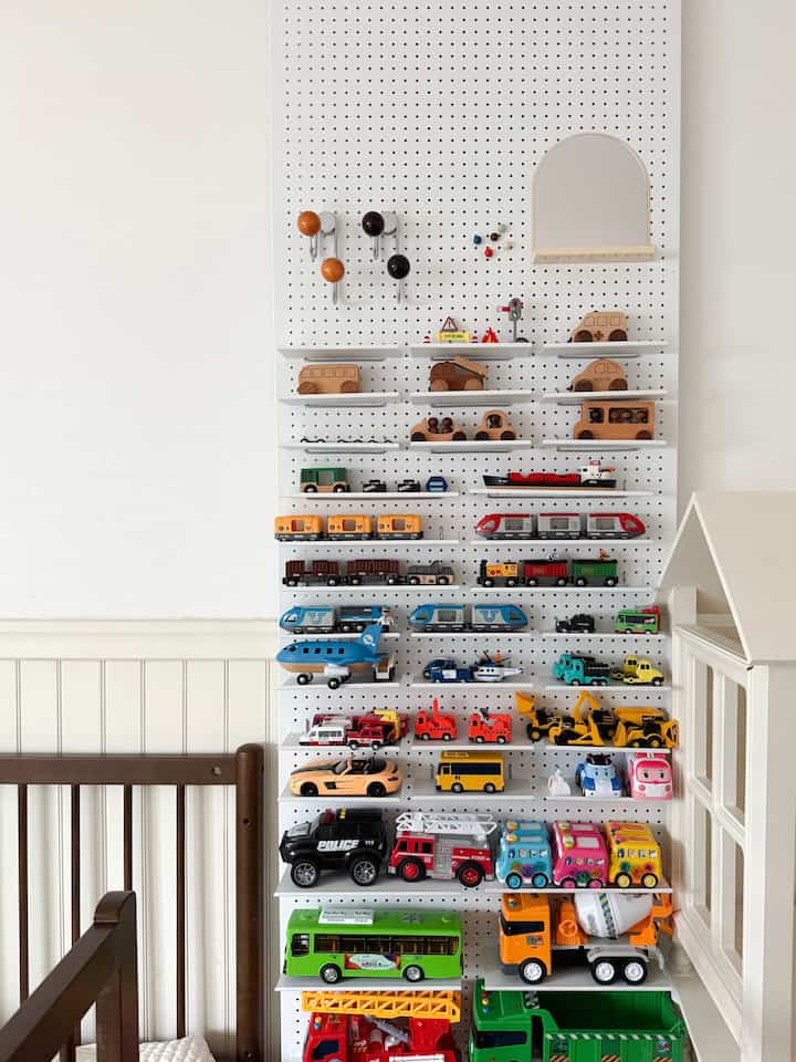 White and brown toned kids' room featuring toy cars neatly organized on a pegboard shelf