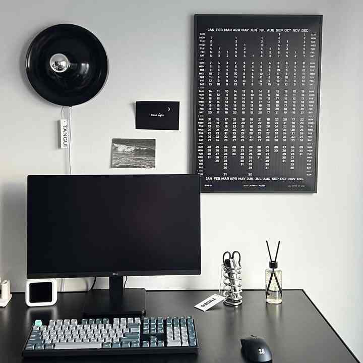 Black and white toned home office space featuring a minimalist desk with diffuser and lamp creating a neat workspace