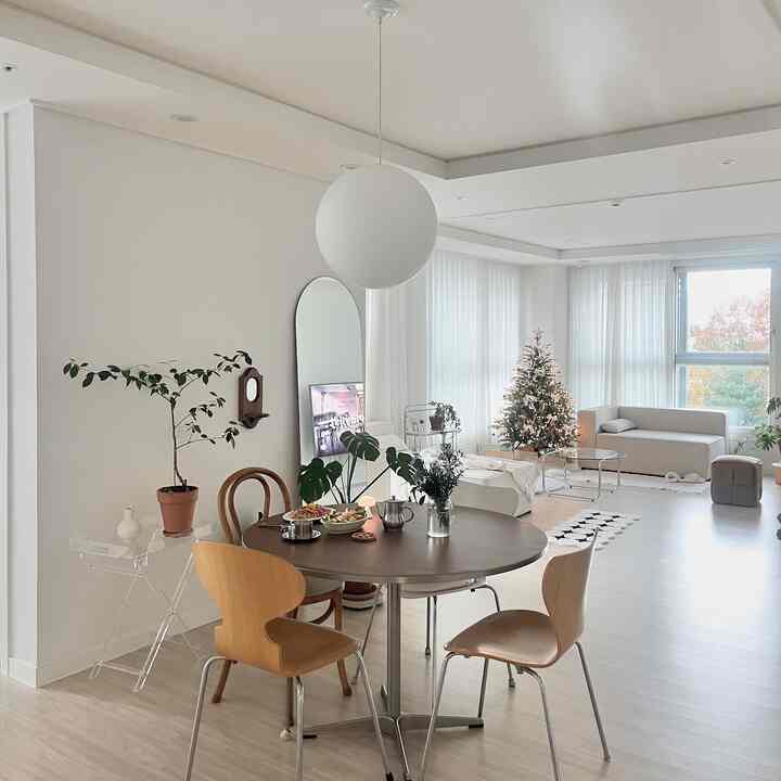 White and natural toned living and dining area featuring a round table and wooden chairs, creating a warm atmosphere