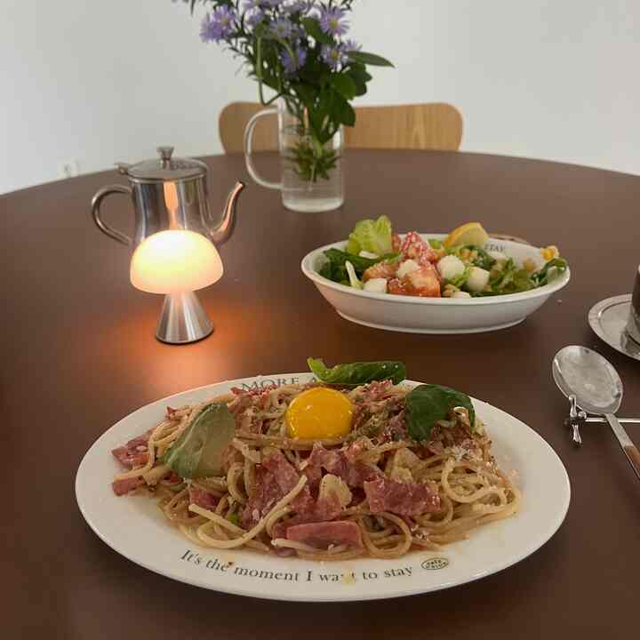Warm brown-toned round dining table featuring a table lamp and plated food in a cozy cafe-style setting