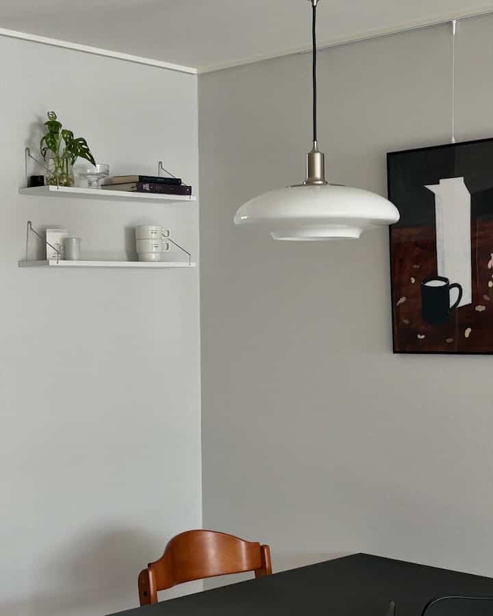 White and gray toned kitchen corner featuring wall shelves and a milk-themed poster with a calm atmosphere