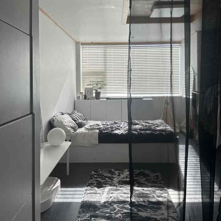 モノトーンの黒と白の寝室、ワンルーム空間にベッドと収納が配置された、清潔感のあるミッドセンチュリーモダンなインテリア