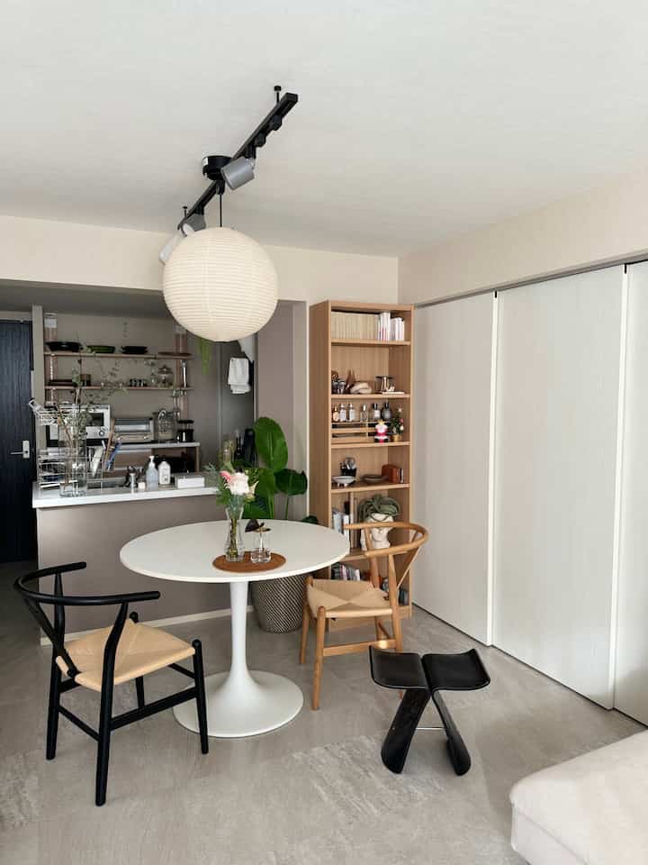 A white and wood-toned living room featuring a round dining table and chairs with a clean minimal Wa-Modern style