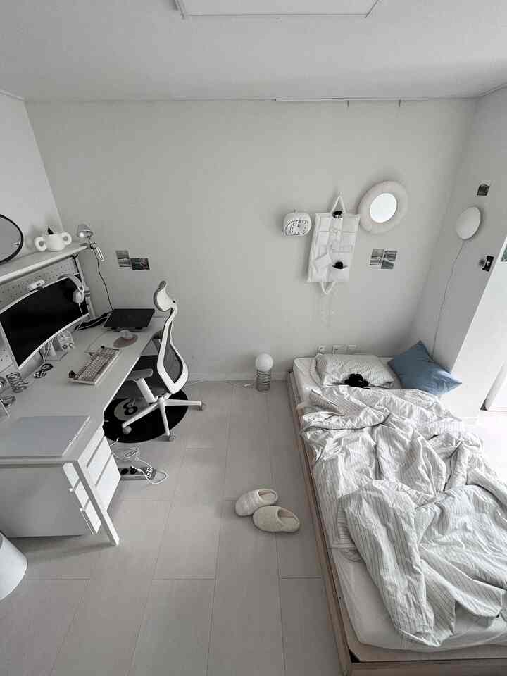 白とグレーのトーンのコンパクトなワンルーム寝室、机とオフィスチェアが配置されたミニマルモダンなインテリア