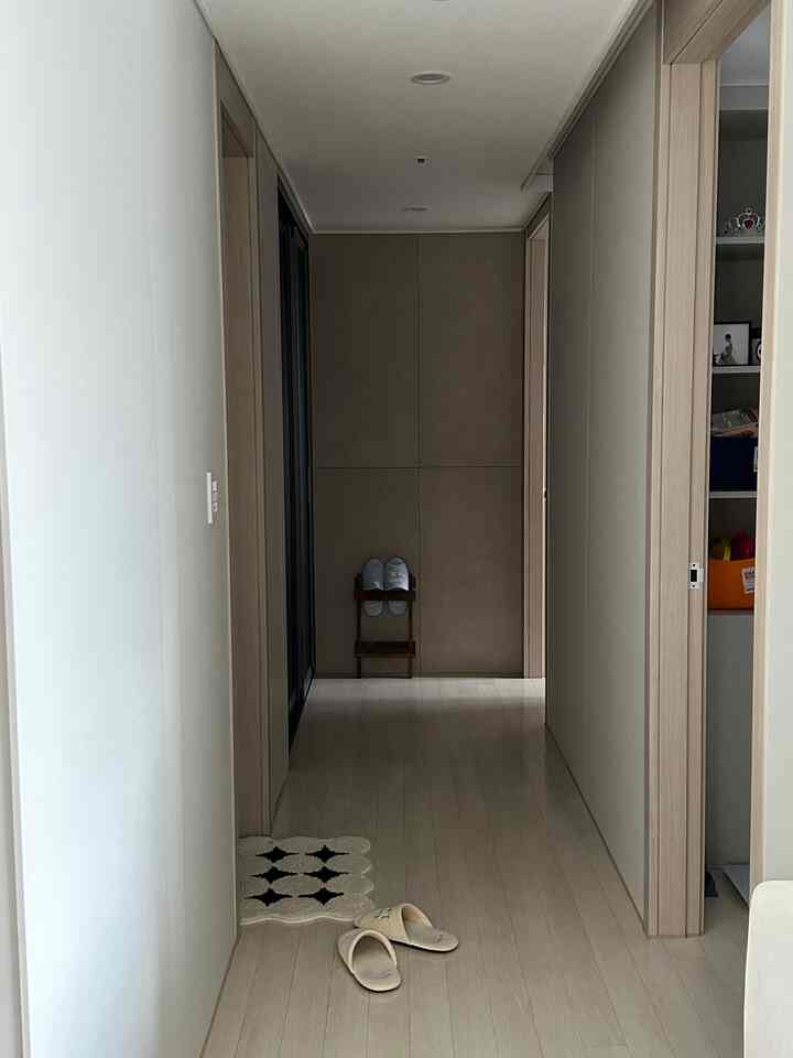 白とベージュのトーンの狭い玄関、スリッパと収納棚が配置された清潔感のあるインテリア