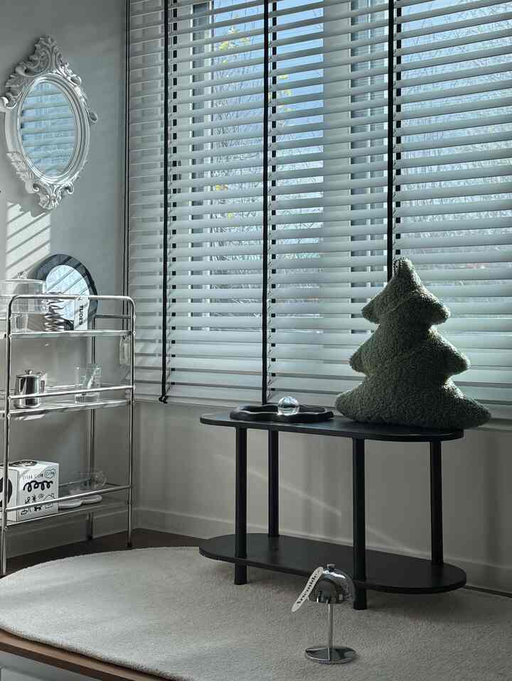 White and silver toned living room featuring blinds, console table, and decorative objects with a modern interior vibe