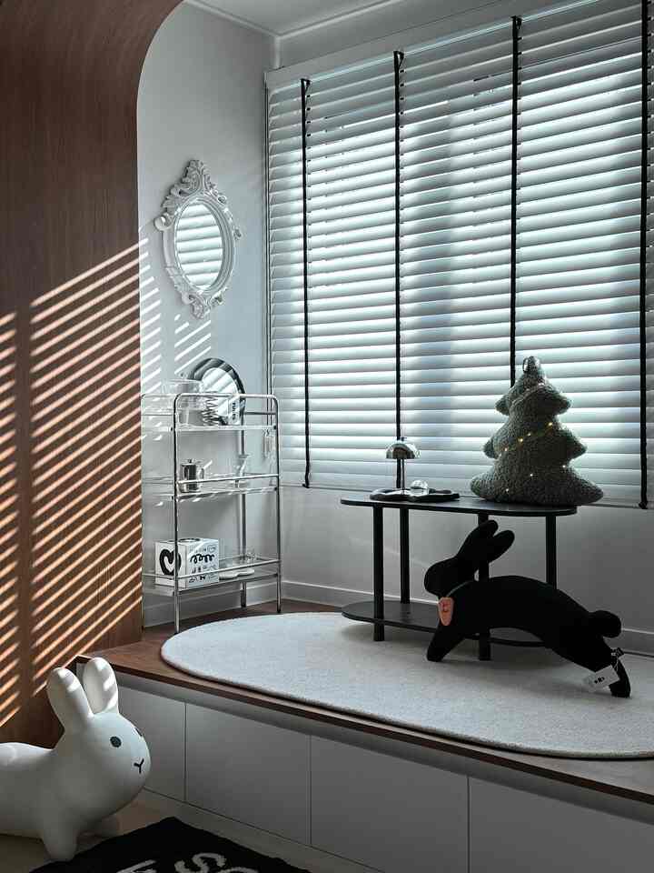 白い壁と木目調のパネルが調和する子供部屋のウィンドウシートスペース、かわいいウサギとツリークッションが配された印象的なインテリア