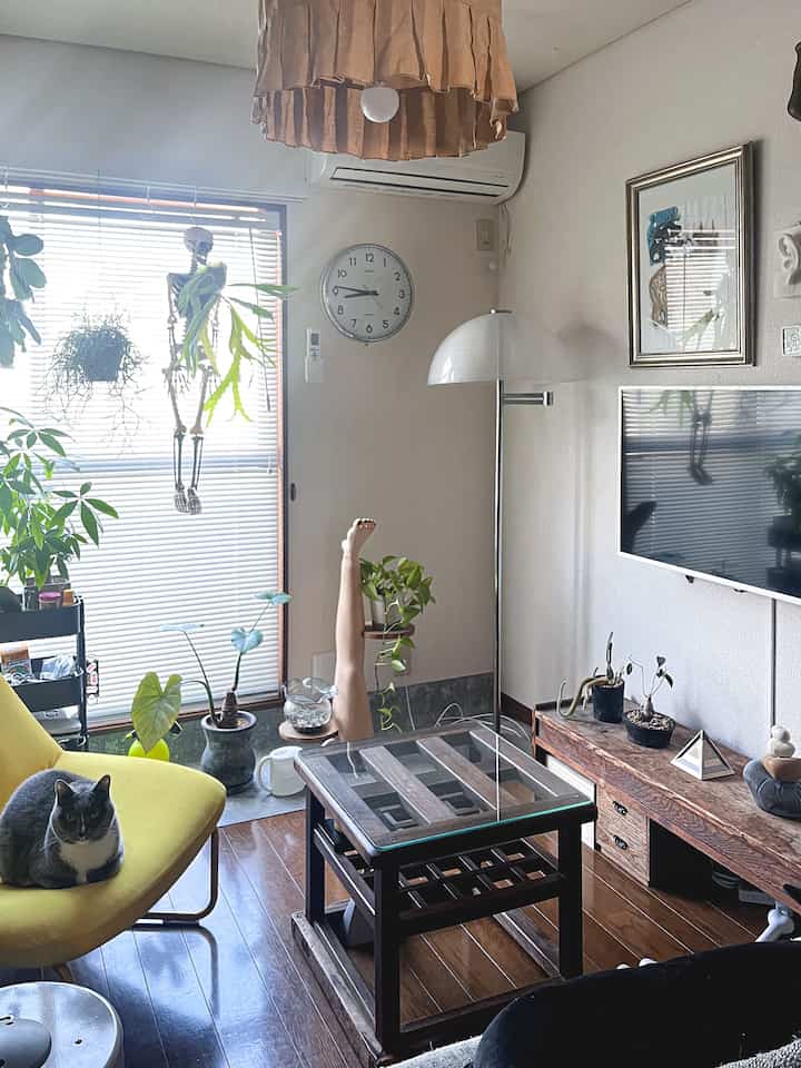 Natural wood-toned living room featuring plants, a yellow armchair, and mounted wall TV creating a cozy atmosphere