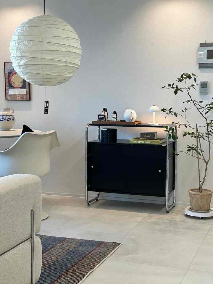 Living room with white background walls and a black cabinet, featuring mid-century modern storage cabinet, sofa, and lighting for a clean interior