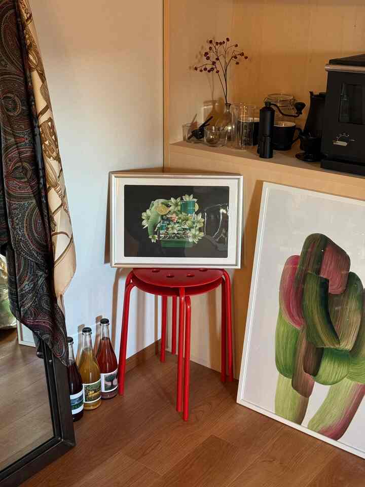 ナチュラルな木目調と赤のアクセントがある1LDKのキッチンコーナー、コラージュアートとロナン・ブルレックのポスターが置かれた印象的な空間