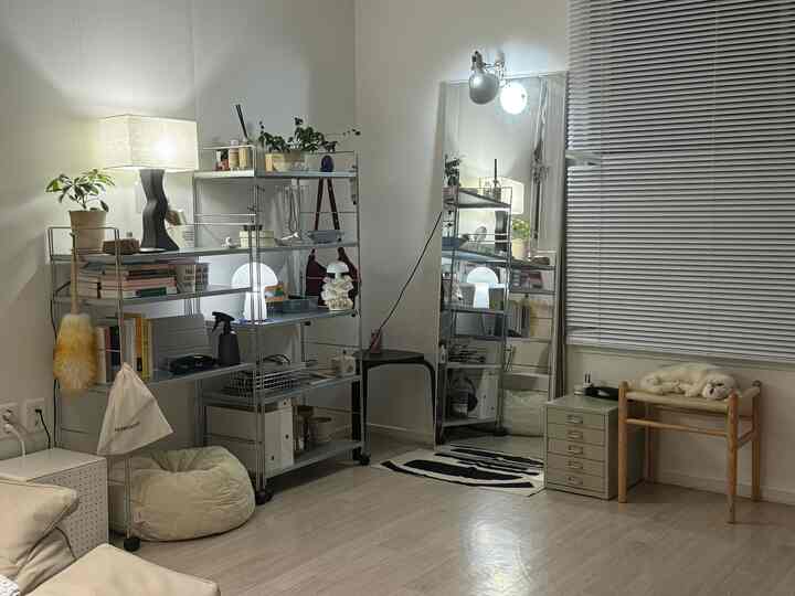 白とナチュラルカラーのリビング、メタルシェルフとスツール、収納とペットの休憩場所が調和した雰囲気のあるインテリア