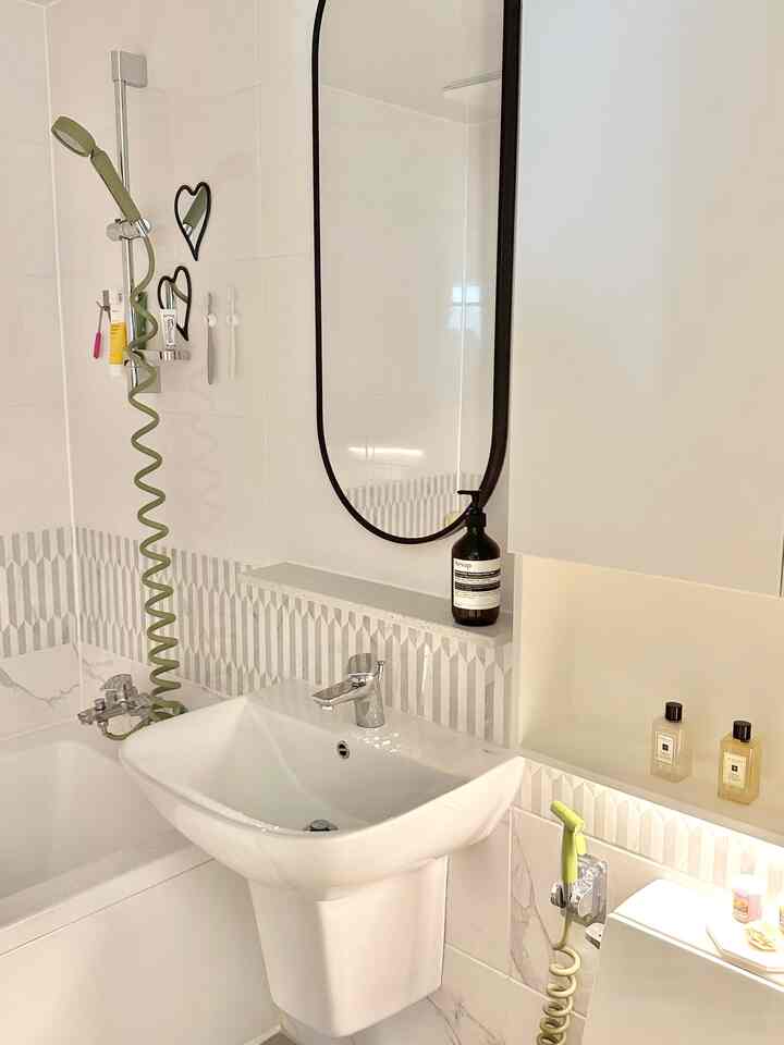 A clean bathroom in white and gray tones featuring a washbasin and practical shelving