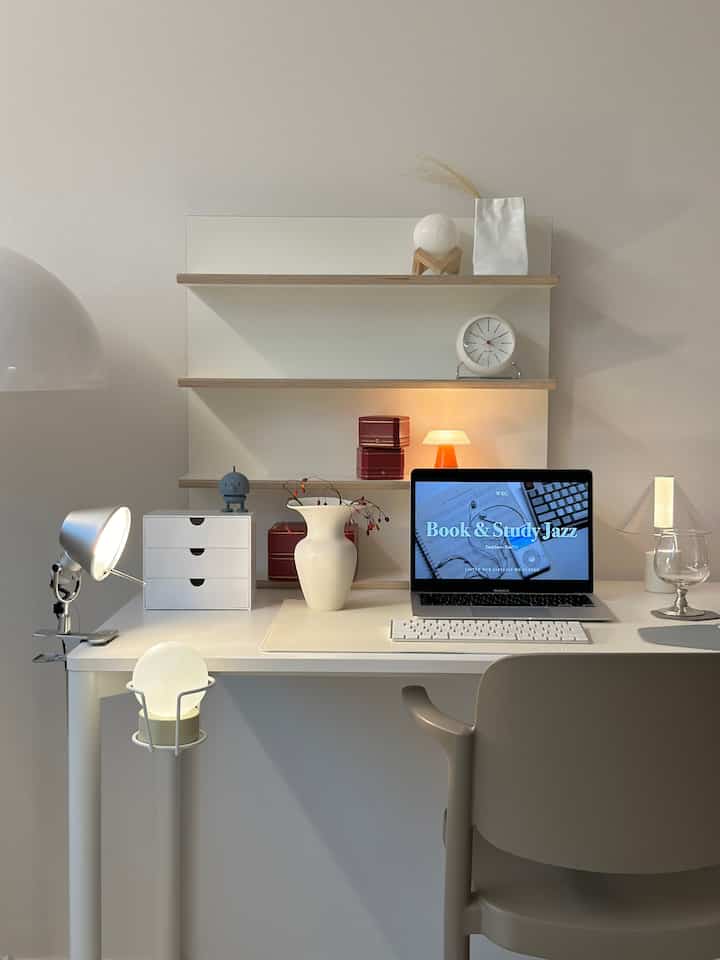 White and beige toned home office featuring a minimal desk setup with ambient lighting creating a cozy atmosphere