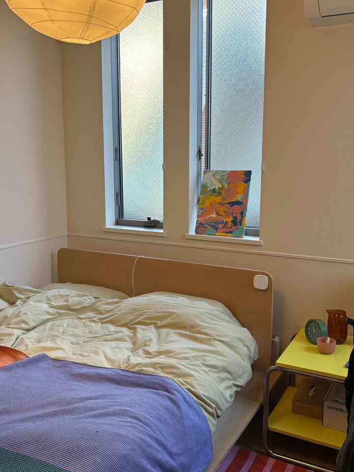 白と黄色のトーンが調和した寝室、木製ベッドとサイドテーブルが配置された雰囲気のあるインテリア