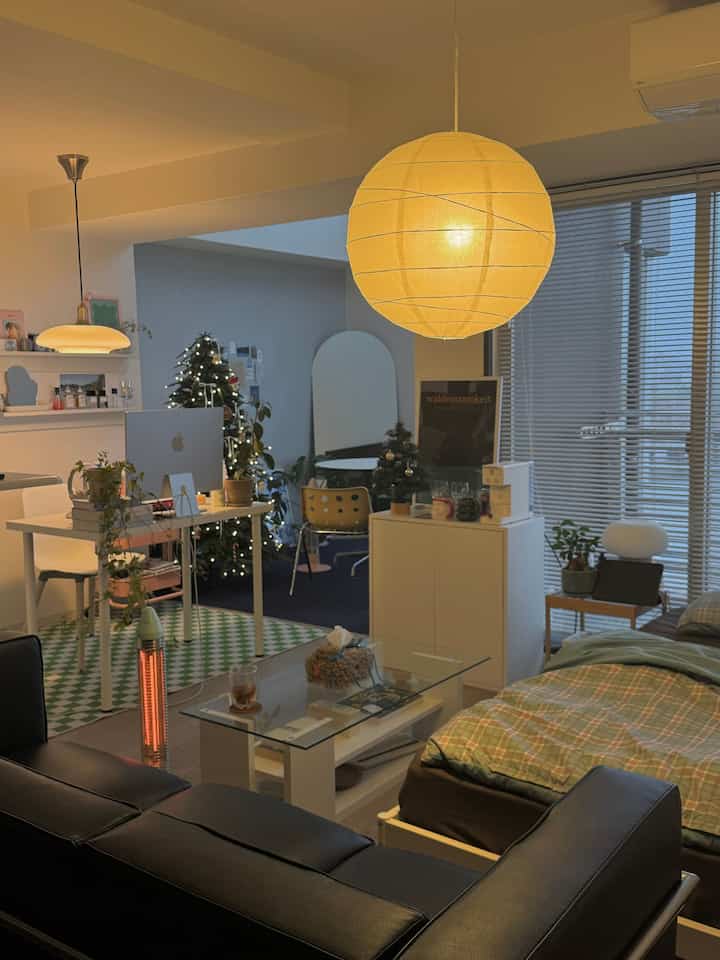 White, black, and green toned studio apartment featuring sofa, bed, a home cafe setup with warm lighting