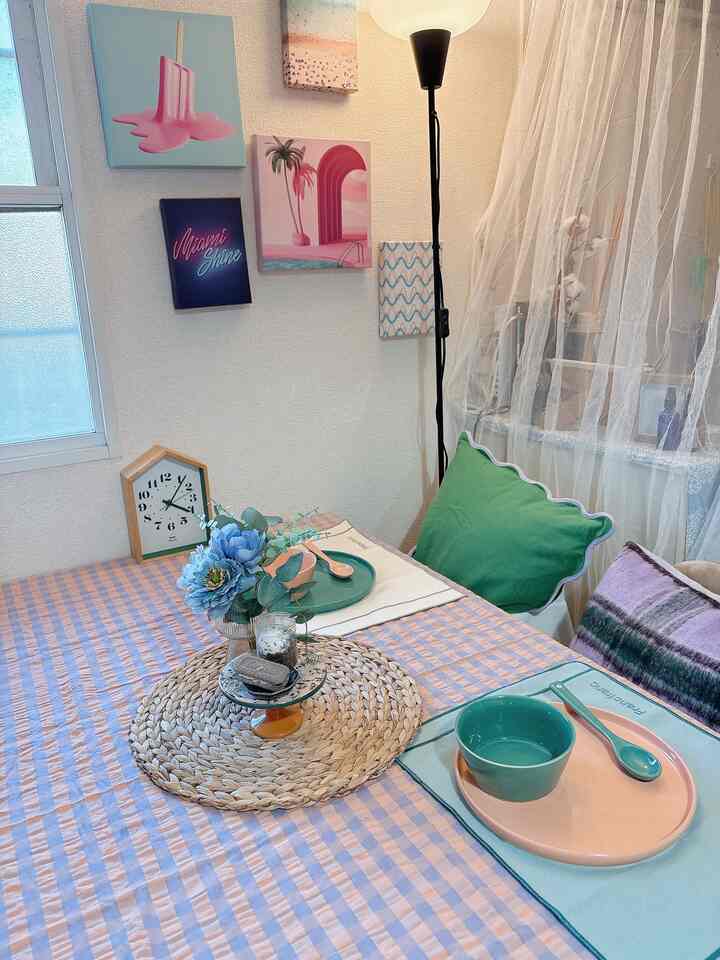 ピンクと青の色調が特徴的な、カフェ風のテーブルセッティングと額縁が配置された居心地の良いダイニングルーム