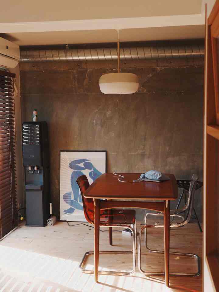 Modern dining room with wood tones and black elements, featuring blinds filtering natural light for cozy atmosphere