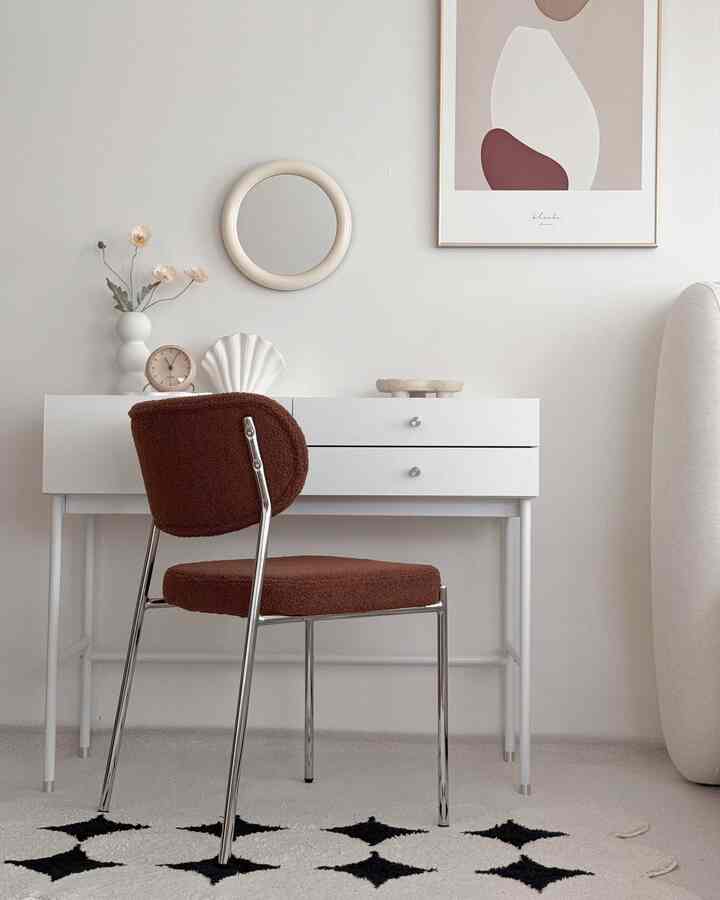Ivory-toned walls and white vanity desk featuring a brown cushioned chair in a simple, minimal bedroom interior