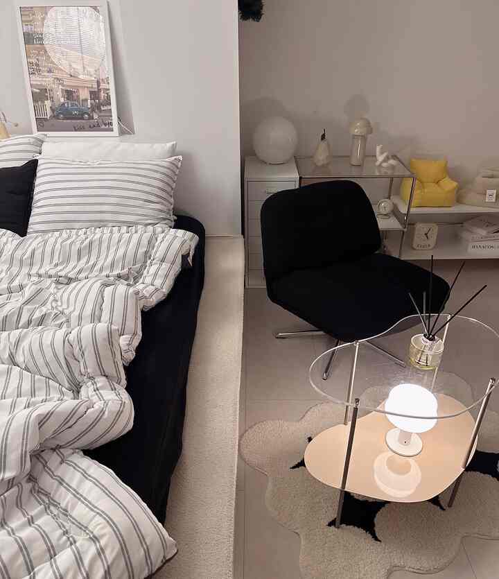 Modern living room with black armchair and bed featuring white walls and bedding creating a clean contrast