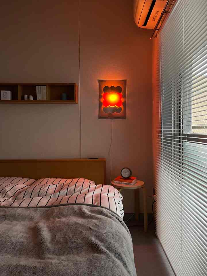 Modern Nordic bedroom with white walls and blinds, illuminated by warm orange poster light for two-person household
