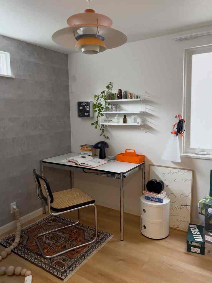 白と茶色のトーンのホームオフィス、シンプルな机と椅子、壁の棚とペンダントライトが配置された印象的な作業空間