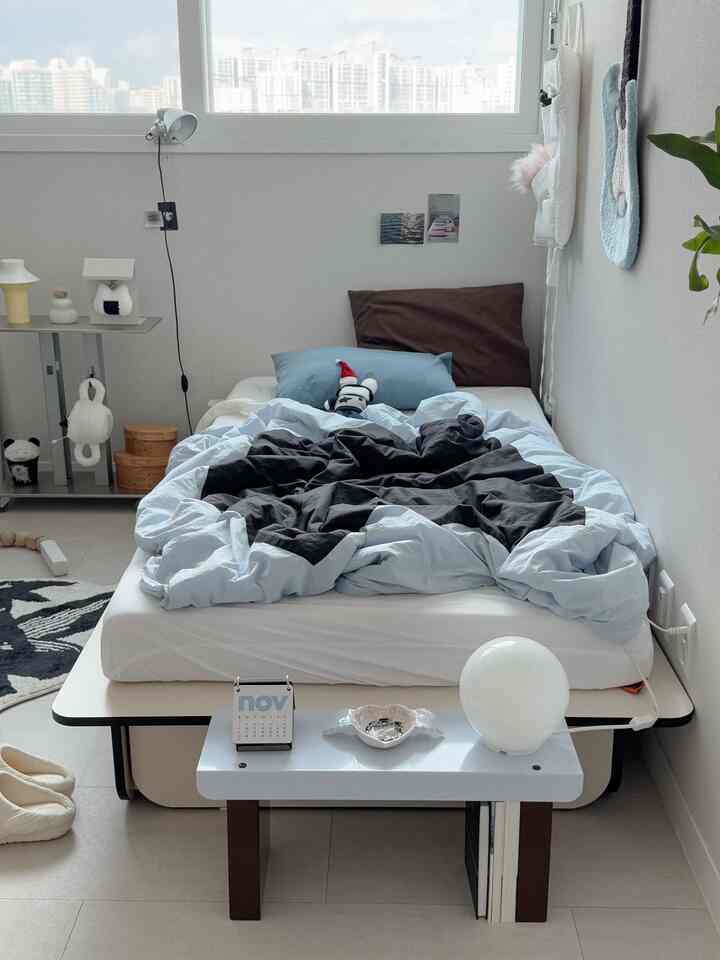 Bedroom in sky blue and brown tones featuring a mini bench nightstand and lighting for a cozy atmosphere