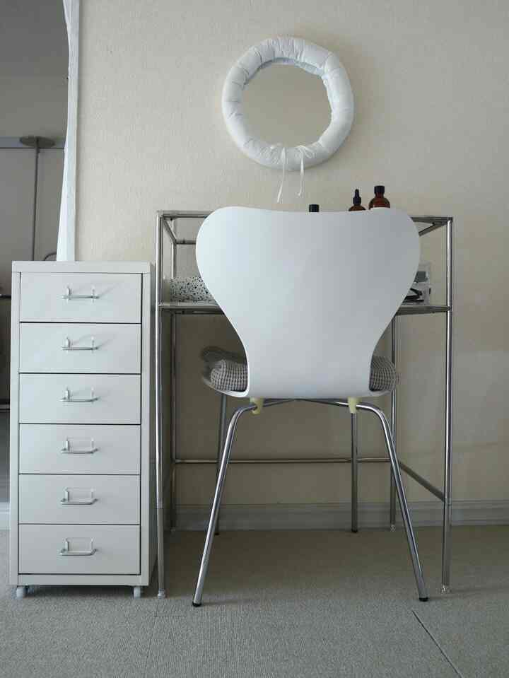 白とメタルを基調にしたシンプルモダンなホームオフィス、スチールのチェストとモジュール化粧台が配置された印象的なインテリア