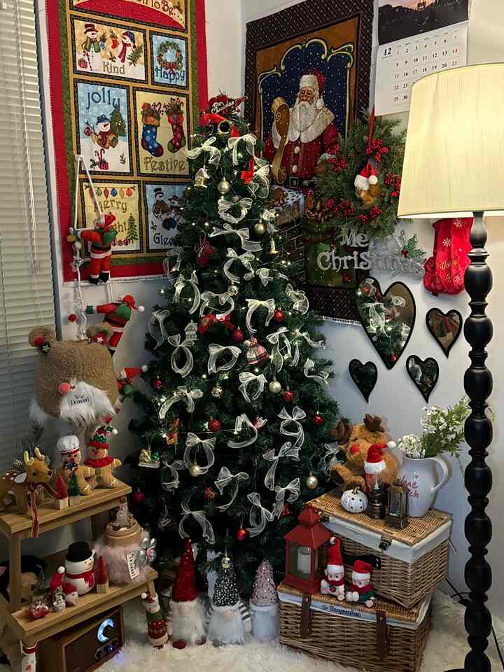 白を基調としたワンルームのリビングコーナーにクリスマスツリーと飾りが配置された暖かいクリスマスインテリア