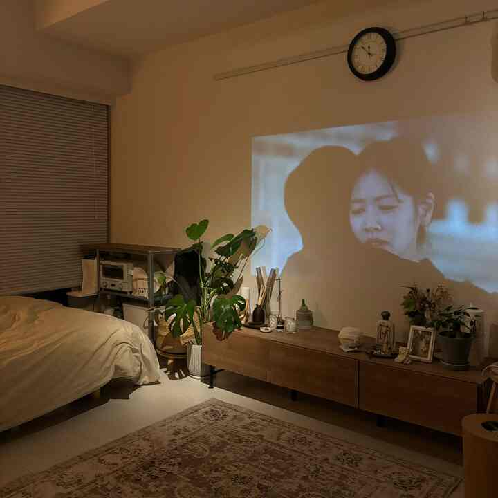 ベージュとナチュラルウッド調の寝室、壁にプロジェクター画面が映し出された雰囲気のあるインテリア