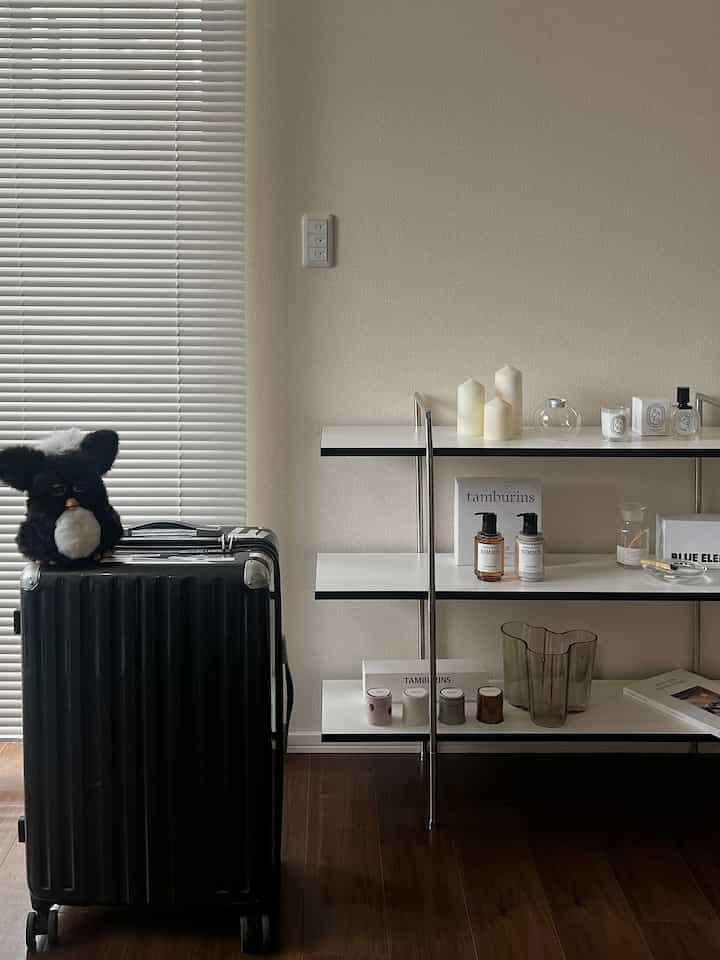 A compact space in white and black tones featuring white blinds and a modern shelf with various decorative items, creating a cozy corner