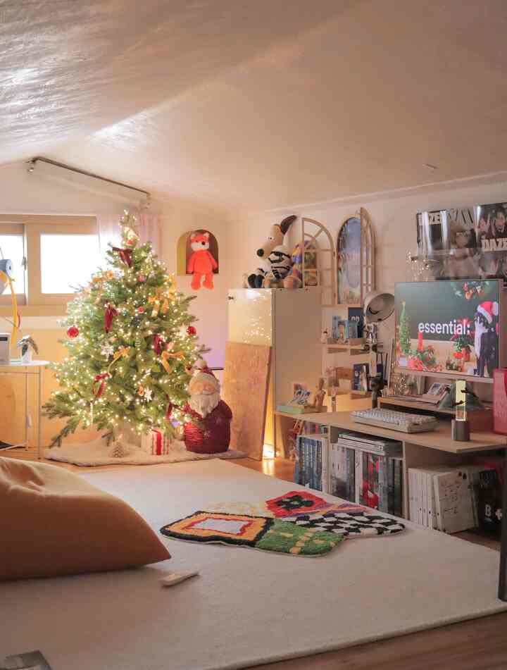 A cozy loft room in white and natural tones featuring a decorated, illuminated Christmas tree centrally placed